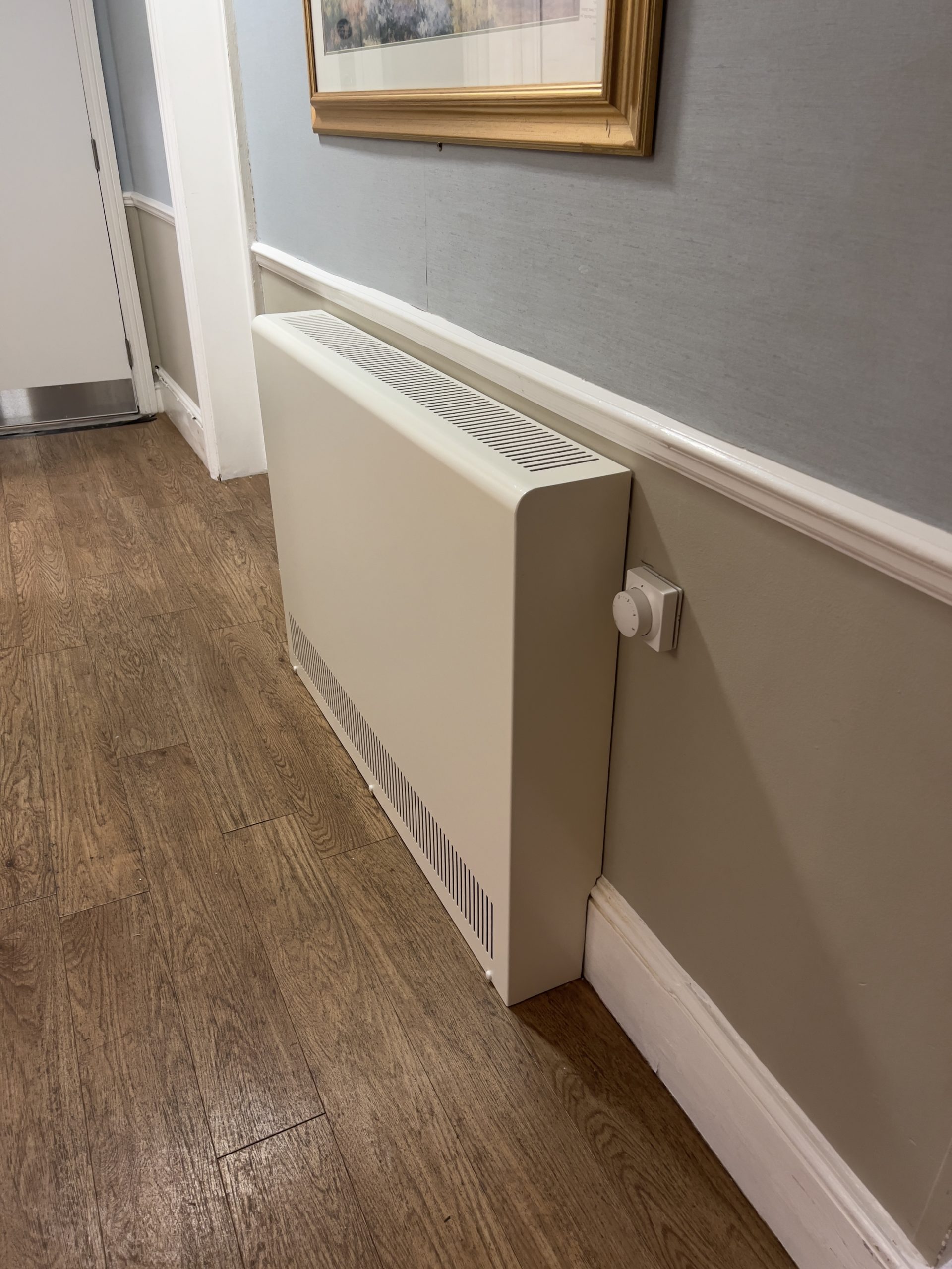 Genuine Coverad Standard Steel casing installed against a wall, showing upper and lower ventilation and the rounded front edge.