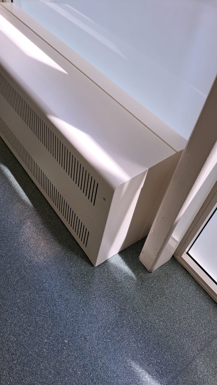 Close-up of a slotted Eazi-Access radiator cover and pre-made back panel beside the glazing frame