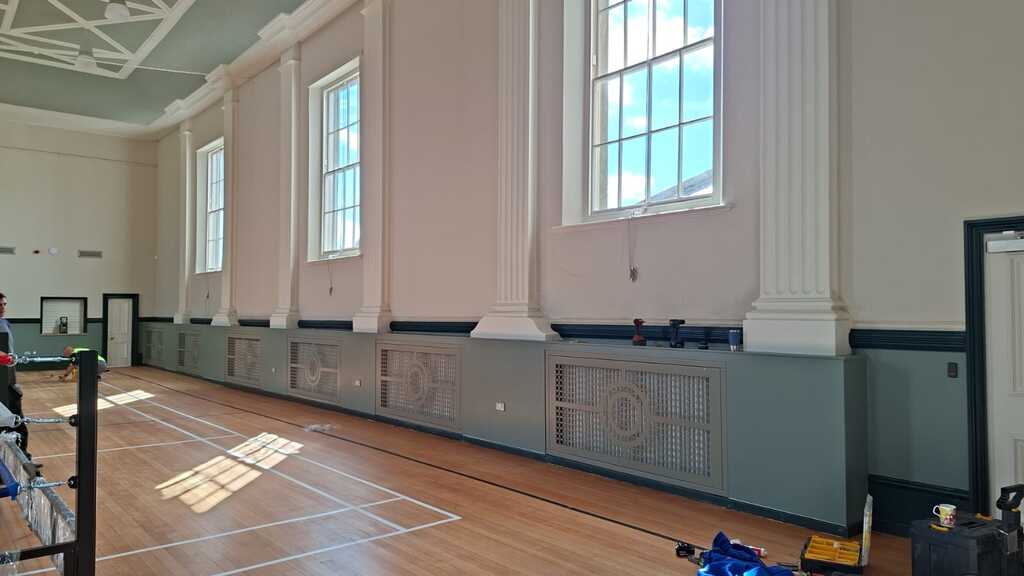 Bespoke decorative radiator panels set into timber framework beneath the windows at Sandown Town Hall