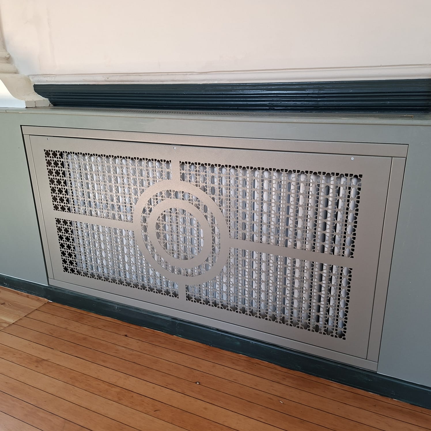 Bespoke radiator front panel with circular detailing and patterned perforations at Sandown Town Hall