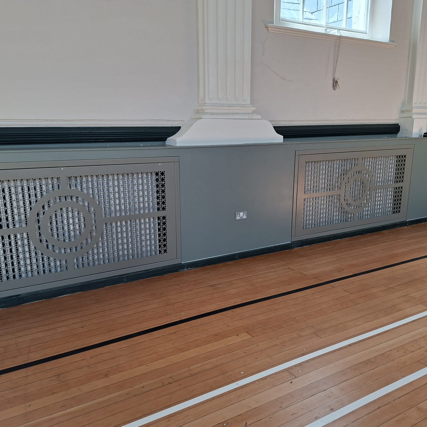 Two decorative radiator front panels fitted into painted timber framework beneath period columns